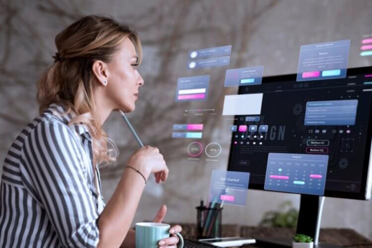 Woman working on digital interface design at a desktop computer with UI/UX elements on screen