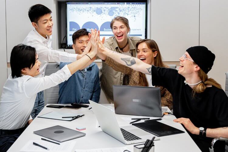 Team of young professionals giving a high-five during a business meeting in a modern office.