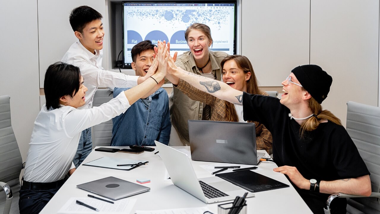 Team of young professionals giving a high-five during a business meeting in a modern office.